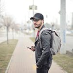 A fashionable young man in Budapest checking his smartphone on a busy street.
